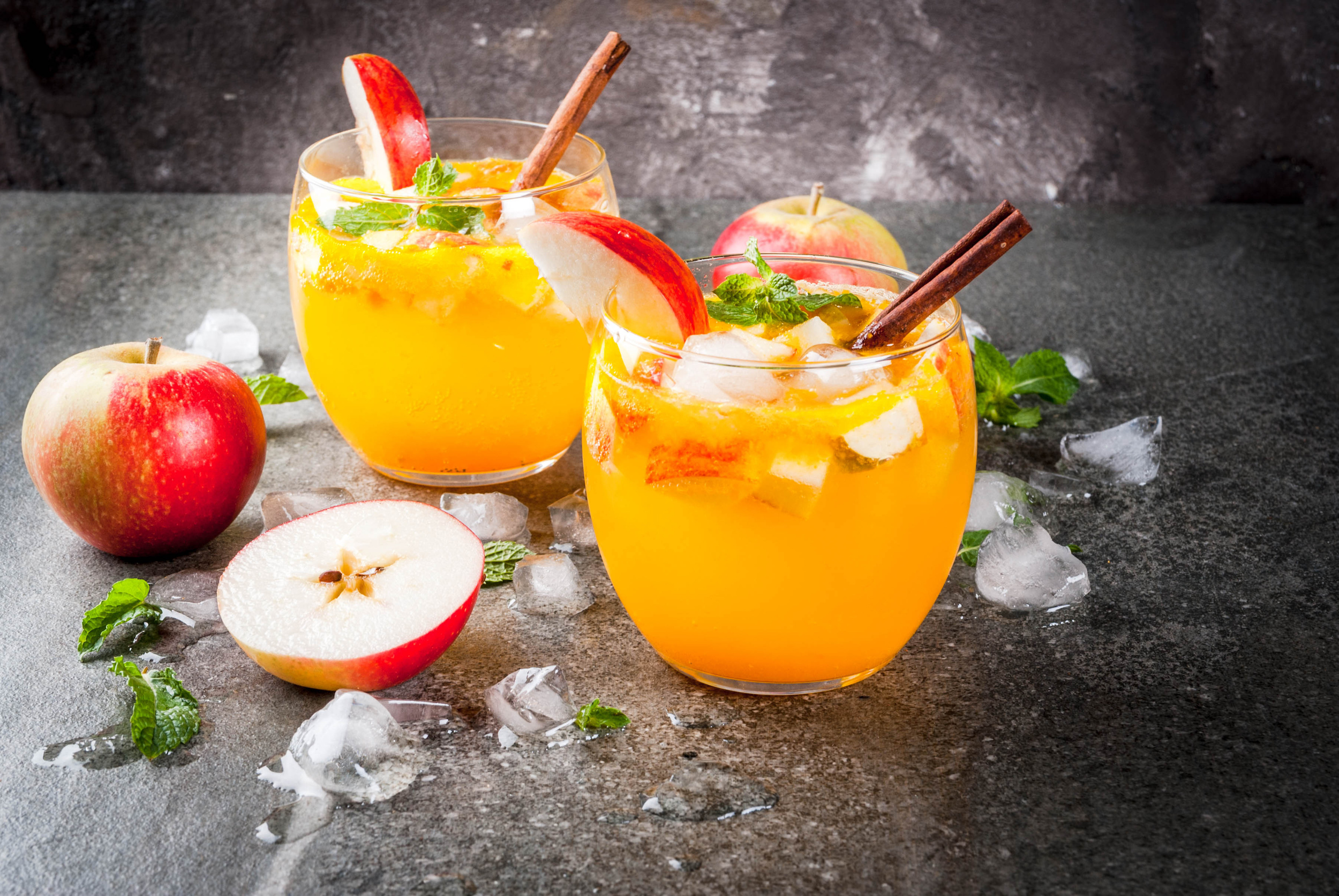 Traditional fall drinks, Apple cider mojito cocktails with mint, cinnamon and ice. On black stone table, copy space